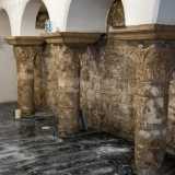 L�interno per� svela una struttura ancora pi� antica, sicuramente di epoca medievale. Sulla destra infatti si stagliano tre grigie colonne in pietra che terminano con eleganti capitelli decorati che reggono una serie di quattro archetti centinati